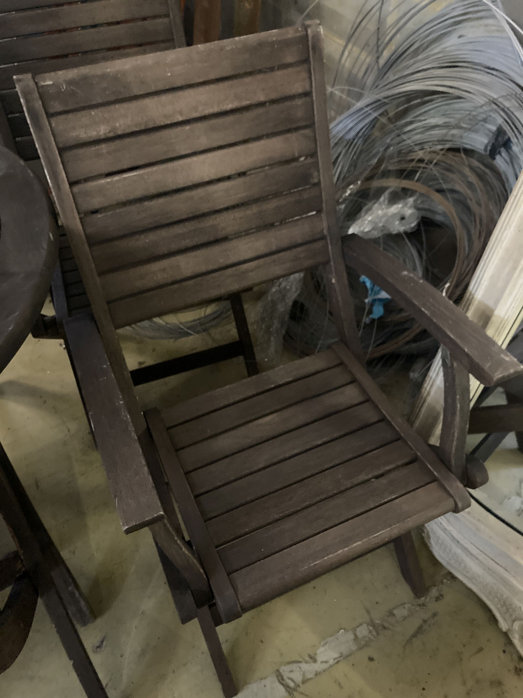 A weathered teak garden table and six teak folding chairs (two with arms)